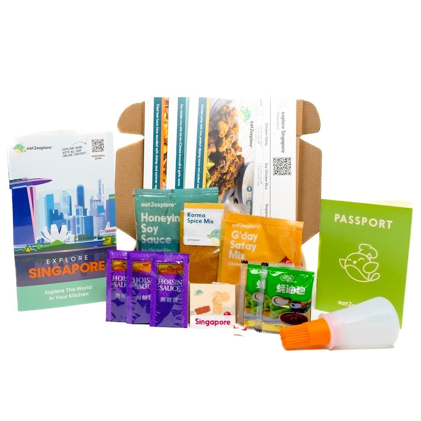 Collection of Singapore-themed products including a box, books, and travel items on a white background